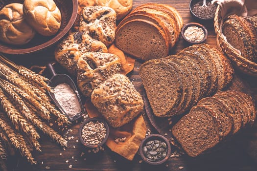Assortment of different kind of cereal bakery - bread, pasties, buns, with healthy seeds on wooden background