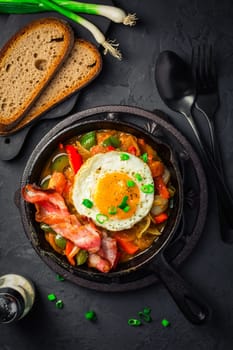 Letscho - tasty Hungarian vegetable stew with peppers, tomatoes and onions, served with bacon and fried egg