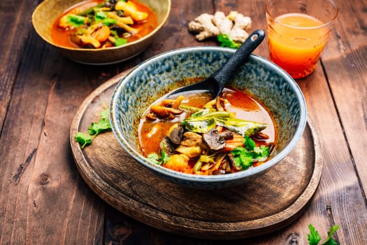 Thai red vegetarian curry with mushrooms and vegetables on wooden table