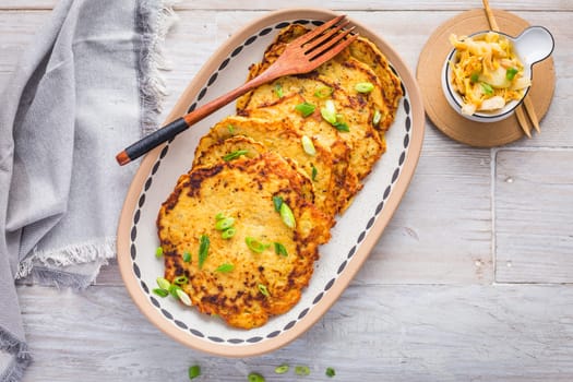 Homemade potato pancakes (Kartoffelpuffer) with cabbage salad and green onions