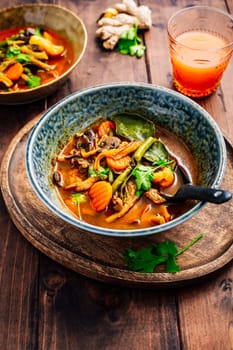 Thai red vegetarian curry with mushrooms and vegetables on wooden table