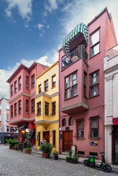 Istanbul, Turkey - May 9, 2023: Facade of colorful wooden residential buildings painted in red and yellow, with wrought iron window, at an alley suited in Kuzguncuk neighborhood, Uskudar district