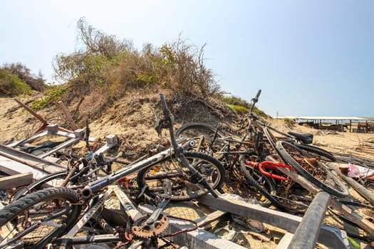 Denizli, Cyprus - August 02, 2018: Sun shining on pile of old rusty discarded bikes laying near beach.