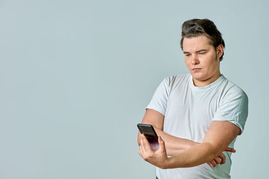 A man looks at the phone screen on a gray background. High quality photo