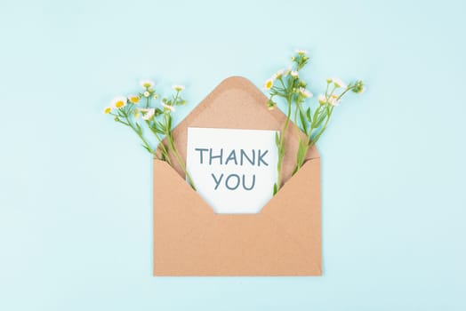 Thank you card in an envelope surrounded by flowers, being thankful, support, help and charity concept, positive attitude