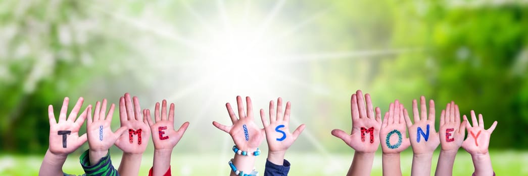 Children Hands Building Colorful English Word Time Is Money. Sunny Green Grass Meadow As Background.