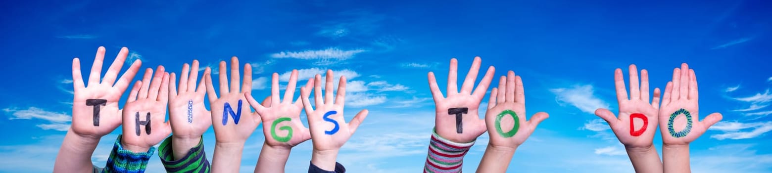 Children Hands Building Colorful English Word Things To Do. Blue Sky As Background.
