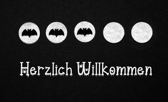 Black Halloween Background With White Dots With Bats and German Text Herzlich Willkommen, Which Means Welcome In English