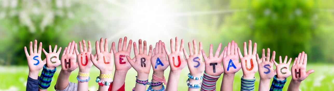 Children Hands Building Colorful German Word Schueleraustausch Means Student Exchange. Sunny Green Grass Meadow As Background.