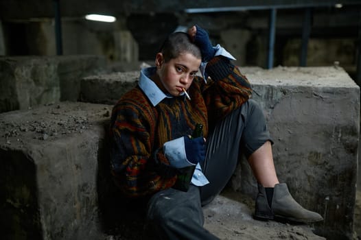 Portrait of young poor helpless woman smoking cigarette. Homelessness and refugee concept