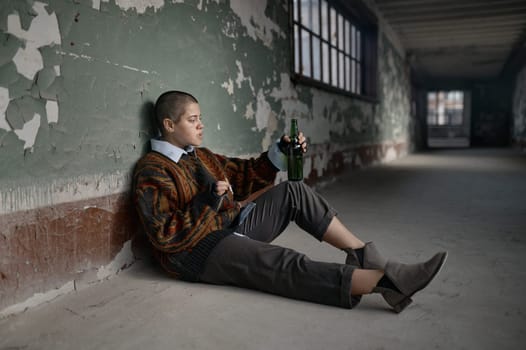 Punk female beggar suffering from nicotine and alcohol addiction on the floor