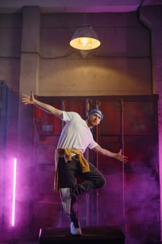 Young guy hiphop performer break dancing in neon club lighting. Male dancer bboying