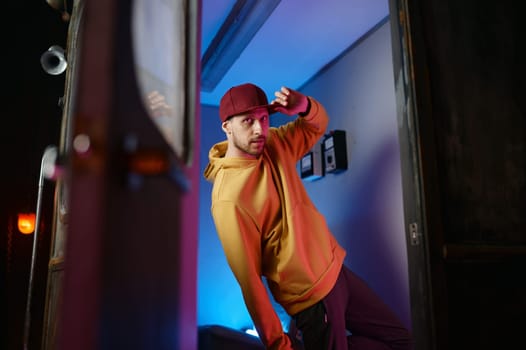 Fashion b-boy breakdancer standing in frozen move in doorway of subway train. Creative freestyle dancer
