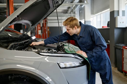 Automobile technician making manual diagnostics checkup of engine for failure. Professional maintenance work at car service
