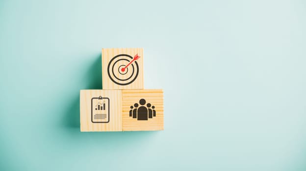 Wooden cube block step on a table with Action Plan, Goal, and Target icons. Success and business target concept. Project management and company strategy on a blue background.