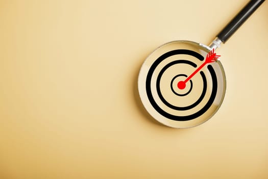 Magnifier glass highlights a target board, showcasing the precision in business objective focus. background and copy space, it conveys the significance of marketing strategies and corporate growth.