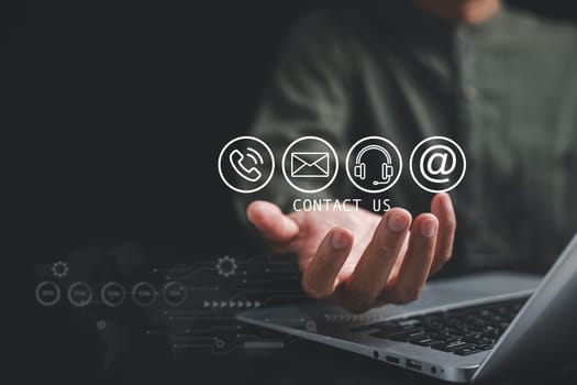 Contact us concept with a businessman's hand holding and pressing on phone, mail, and message icons. Customer service call center on a banner. Copy space for communication background