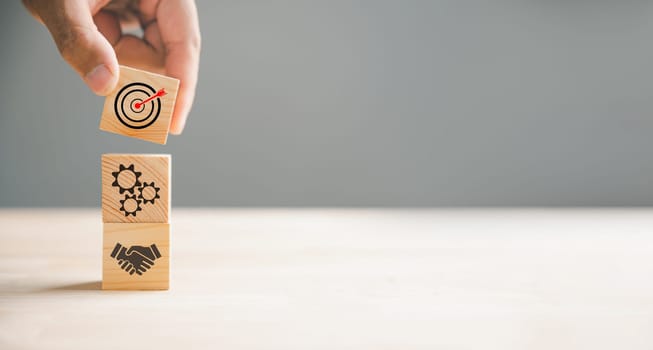 Wood block stacking guided by a hand showcases a business strategy and Action plan, targeting the business concept. It symbolizes business development and emphasizes growth and success.