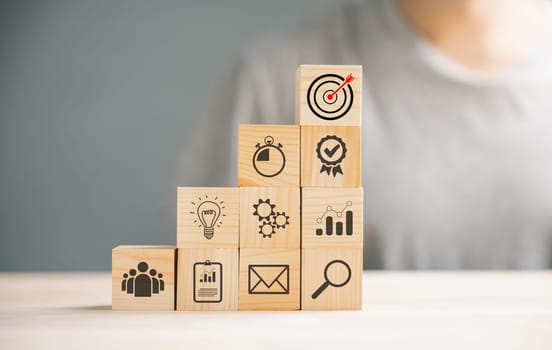 Wooden cube block step on a table with Action Plan, Goal, and Target icons. Success and business target concept. Project management and company strategy symbolize growth.