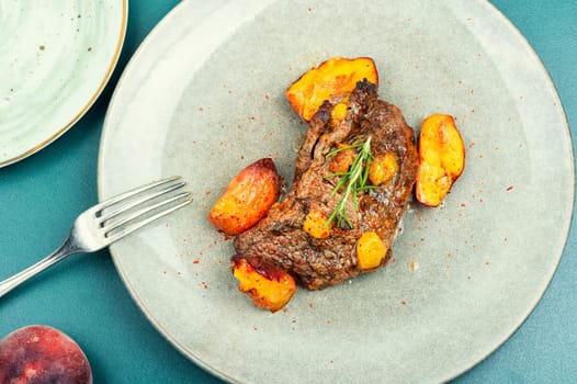 Succulent beef steak with peach in fruit marinade. Close-up.