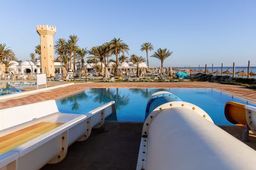 Small aquapark sliders with pool and palm trees at the morning, Tunisia