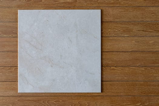 Light gray square marble sign Hanging on a brown horizontal plank wall Or you can look at it as a marble tray placed on a wooden floor taken from above. up to imagination There are many copy spaces.