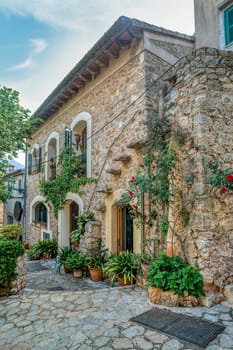 Narrow street in the Valldemossa with lots of ubiquitous flowers. Architectural treasures - Magic of Valldemossa's historic center and its Mediterranean architecture. Balearic Islands Mallorca Spain.