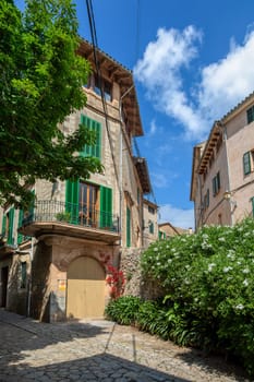 Narrow street in the Valldemossa with lots of ubiquitous flowers. Architectural treasures - Magic of Valldemossa's historic center and its Mediterranean architecture. Balearic Islands Mallorca Spain.