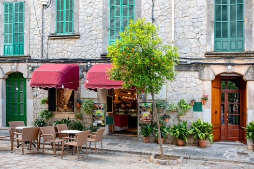 A cafe in a narrow street in the historic center of Valldemossa. Traditional Mediterranean architecture combined with lots of ubiquitous flowers. Balearic Islands Mallorca Spain.