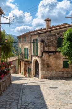 Narrow street in the Valldemossa with lots of ubiquitous flowers. Architectural treasures - Magic of Valldemossa's historic center and its Mediterranean architecture. Balearic Islands Mallorca Spain.