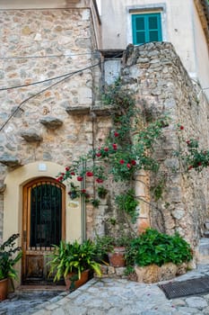 Narrow street in the Valldemossa with lots of ubiquitous flowers. Architectural treasures - Magic of Valldemossa's historic center and its Mediterranean architecture. Balearic Islands Mallorca Spain.