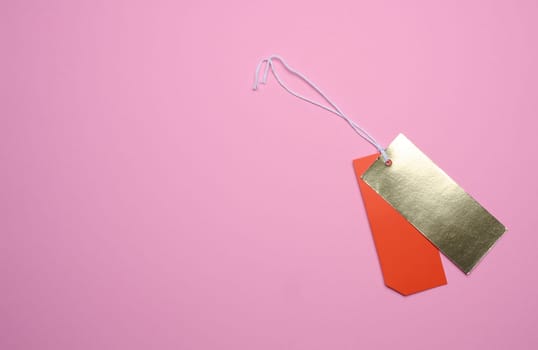 Price tag with a white string for clothing and merchandise on a pink background. Copy space