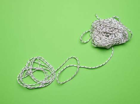 White laundry rope on a green background, top view
