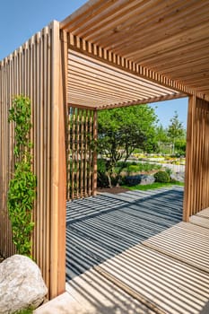 Modern wooden arbor. Modern wooden gazebo in courtyard, backyard. Urban gazebo, relaxing garden design.
