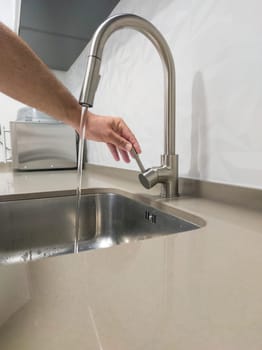 Male hand opening the kitchen sink tap. Selective focus