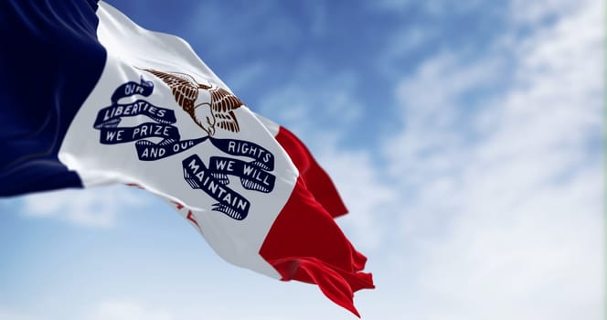 Iowa state flag waving in the wind on a clear day. Three vertical stripes of blue, white, and red, with a bald eagle in the center. 3d illustration render. Fluttering fabric. Selective focus