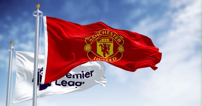 Manchester, UK, July 2 2023: Manchester United Football Club and Premier League flags waving on a clear day. Premier League pro team. Illustrative editorial 3d illustration render. Selective focus