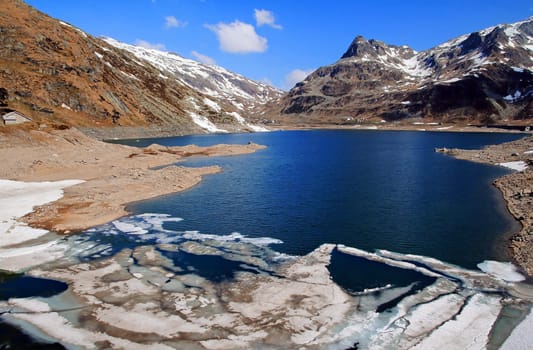 Summer on the Splgen in Switzerland. Ice floes on a lake in high mountains