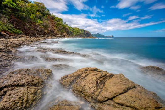 Long exposure, pacific ocean waves on rock in Playa Ocotal, El Coco Costa Rica. Famous snorkel beach. Picturesque paradise tropical landscape. Pura Vida concept, travel to exotic tropical country.