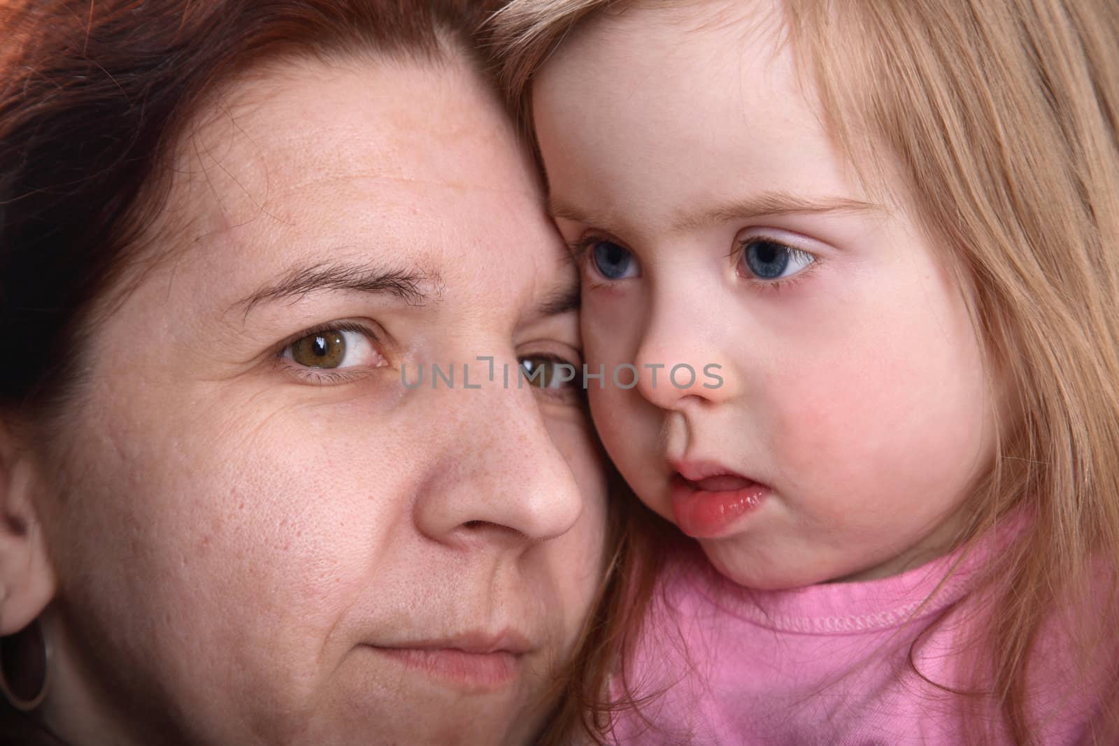 A closeup portrait of a young girl with Down Syndrome and her mother.