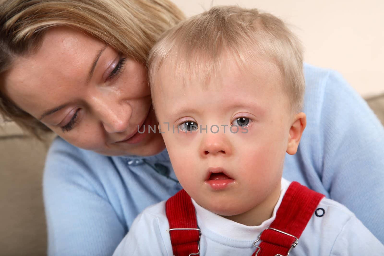 A closeup portrait view of a young boy with Down Syndrome and his mother.