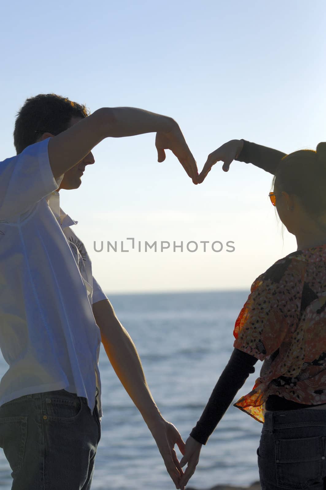 Couple drawing an heart with their arms