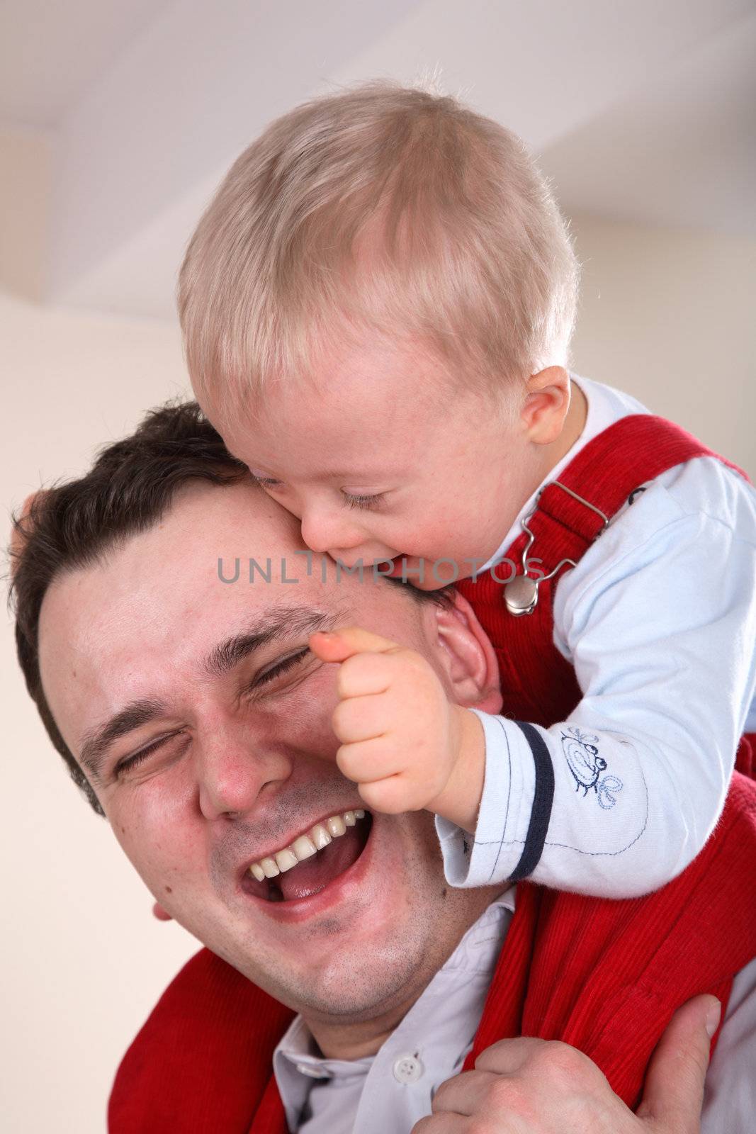 Laughing father with his young handicapped son sitting on his shoulders.