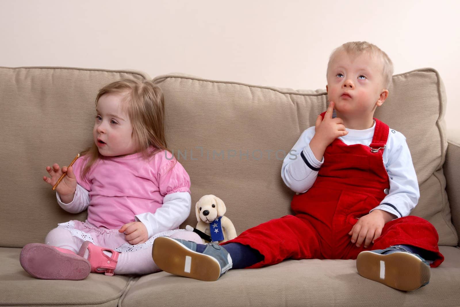 A little boy and girl with Down syndrome sitting on a sofa