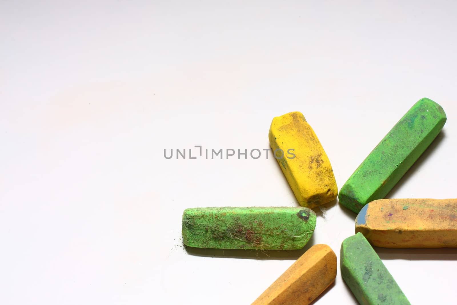 A few used yellow and green chalk pastels on white