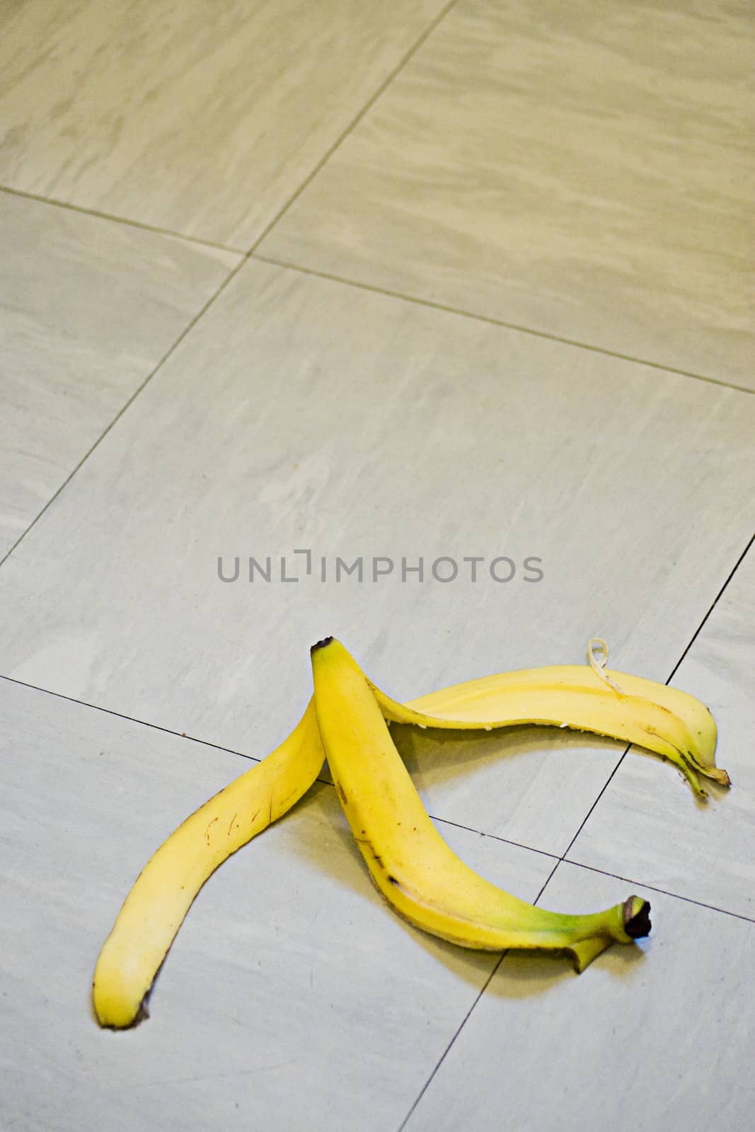 A banana skin lying on a tile floor ready for someone to slip