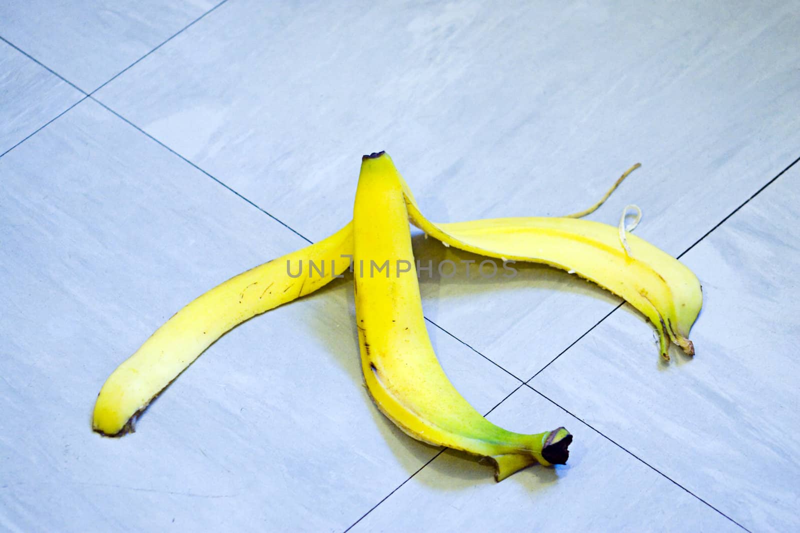 A banana skin lying on a tile floor ready for someone to slip