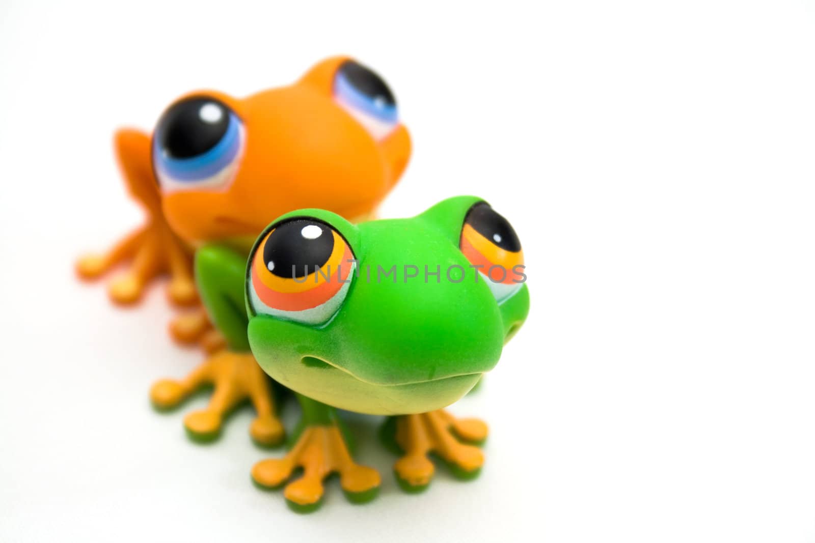 Two plastic frog toys, one orange and one green, isolated on white background.
