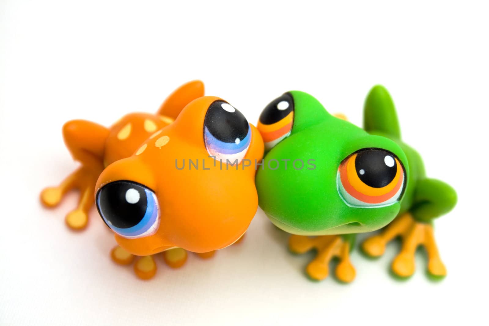 Two plastic frog toys, one orange and one green, isolated on white background.