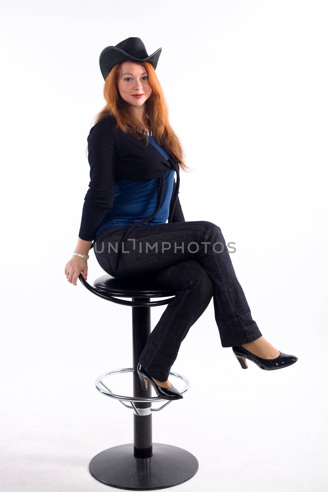Young girl with  black hat sitting on chair on white background
